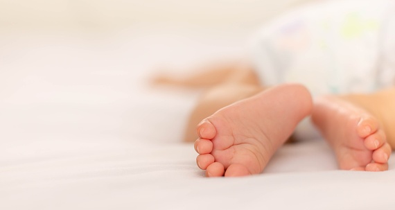 newborn baby's feet sleeping on a white bed with copyspace.