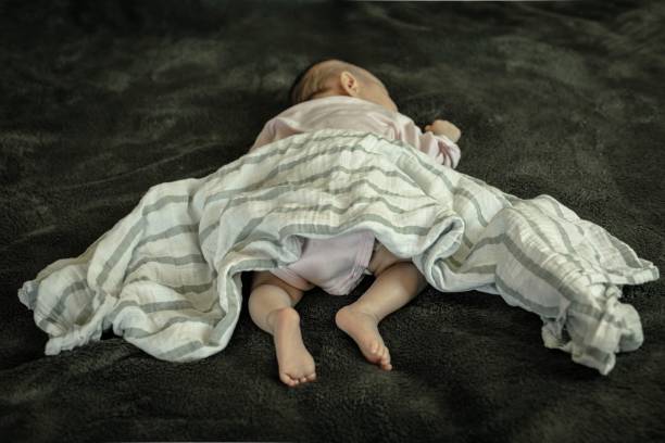 a infant baby sleeping in dangerous position on stomach and loose blanket. sudden infant syndrome. - baby lying down sleeping asian ethnicity imagens e fotografias de stock