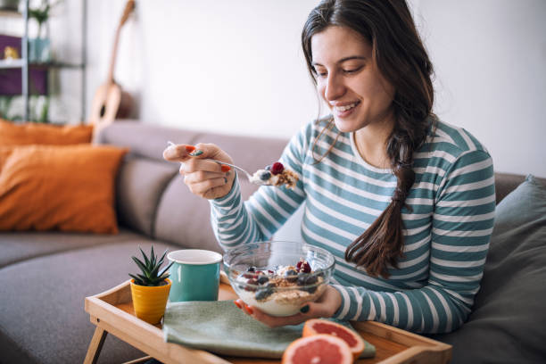 lächelnde frau beim frühstück am morgen zu hause - granola breakfast dieting food stock-fotos und bilder