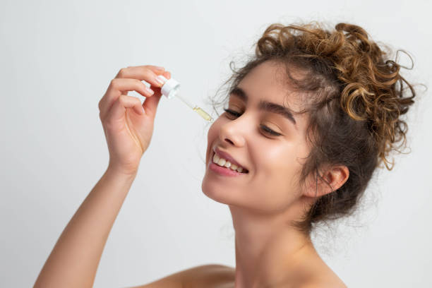 foto de una mujer hermosa aplicando suero a la piel limpia de su cara contra las arrugas de la cara - vitamin c fotografías e imágenes de stock