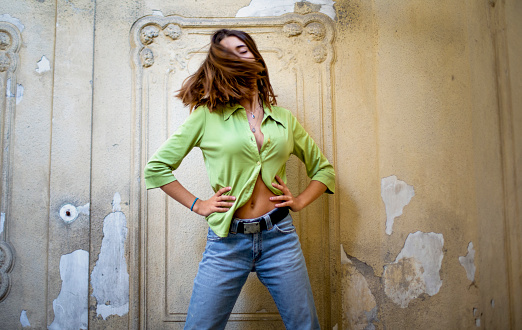 Teen girl young shaking her hair. Standing with her hands in waist in cool attitude  wearing jeans and green shirt.  Medium shot