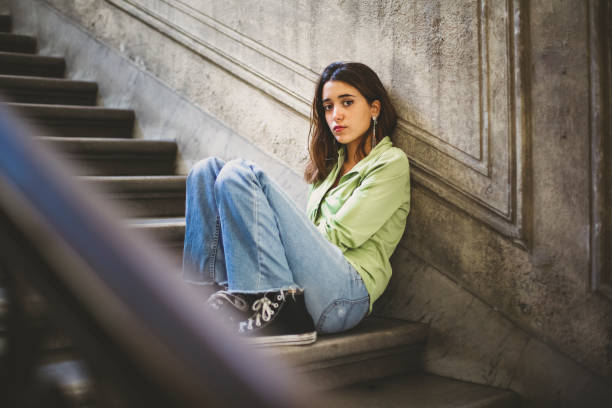 istock beautiful young woman locking at camera sitting on a ladder 1356241044