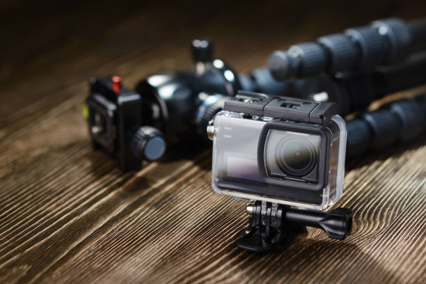 Black action camera on brown wooden tabletop.
