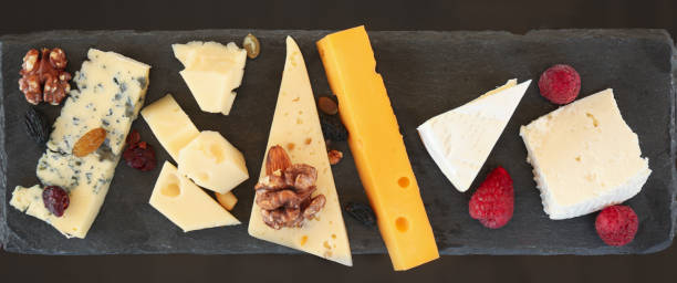 istock Different types of delicious cheeses and snacks on slate plate, flat lay 1356245333