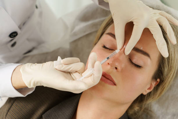 Woman during facial filler injections in aesthetic medical clinic stock photo