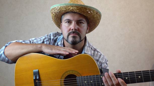 istock A man in a hat sits with a guitar 1356246583