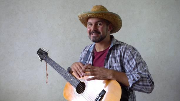 istock A man with a hat smiles and bangs on a guitar 1356246619