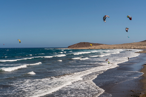 Surfers in the air over surfing beach El Medano in south Tenerife