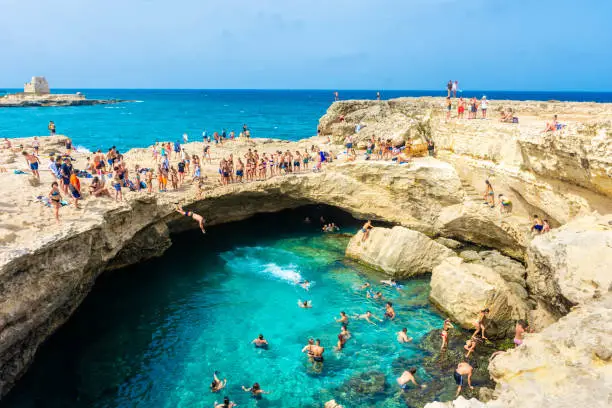 SALENTO, ITALY, 11 AUGUST 2021: People diving in the crystal clear water of the Grotta della Poesia (Poetry Cave)