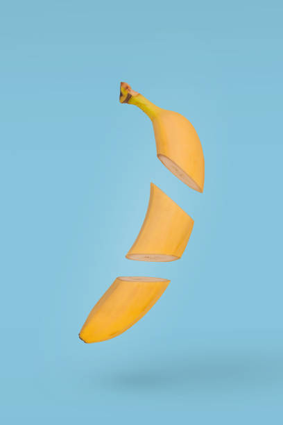 istock Fresh sliced banana floating in air isolated on bright blue background. 1356253144