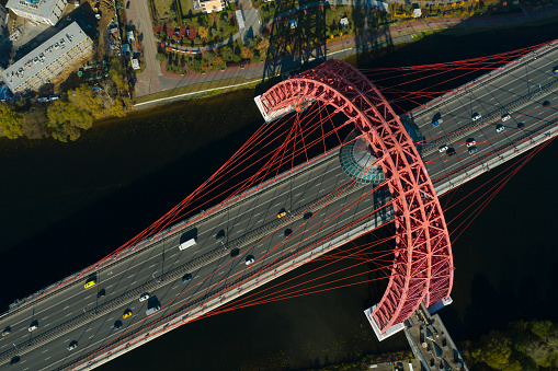 MOSCOW, OCT.10,2021: Aerial view on modern red cable arch bridge above highway with automobiles, cars above the river. Drone photography. Scenic Bridge. Beautiful cityscape