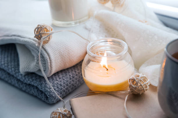 istock Burning candles and white sweaters on windowsill. Cozy autumn and winter concept, window with blinds... 1356256576