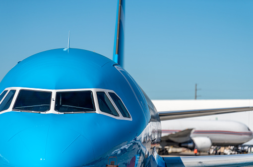 Blue airplane waiting on the ground for its next flight.