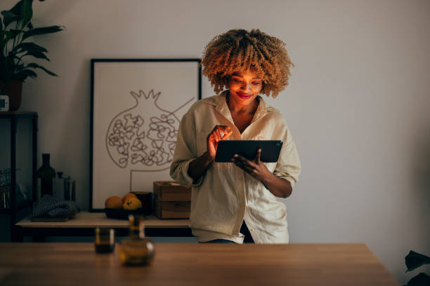 istock Smiling Woman Using Digital Tablet at Night 1356258359