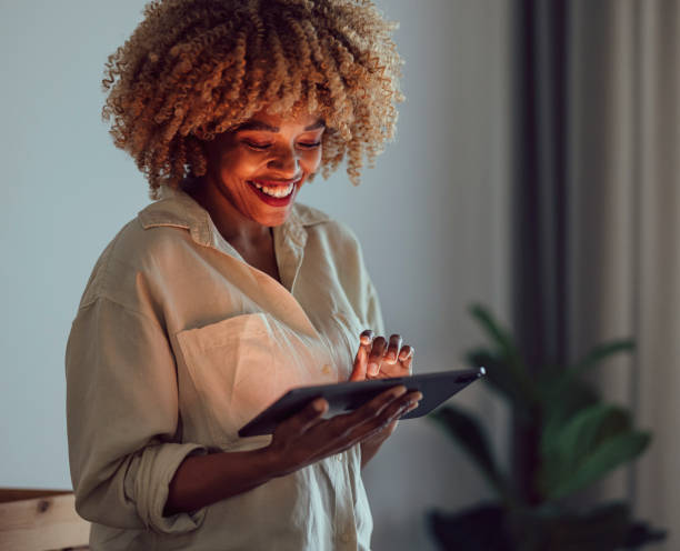 istock Happy Afro-American Woman Standing and Smiling While Looking at a Digital Tablet 1356258387