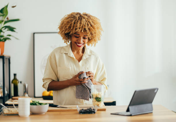 istock Smiling Woman Wipes Hands With a Rag in the Kitchen 1356258395