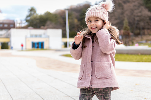 Cheerful child wearing a stylish coat smiling on autumn day