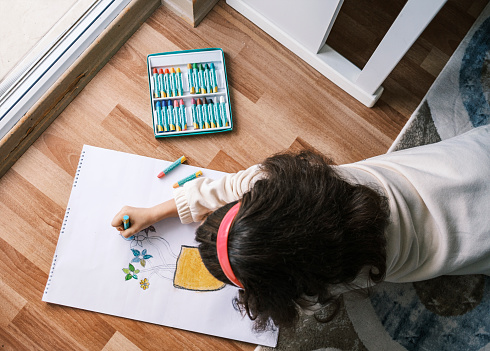 Cute happy little girl drawing at home