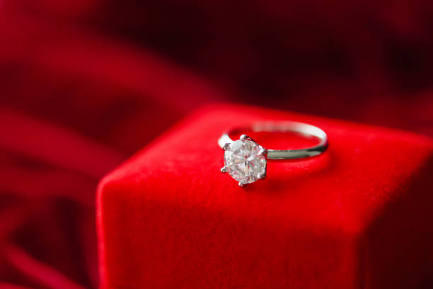 istock Diamond ring with jewelry gift box on red fabric background 1356271164