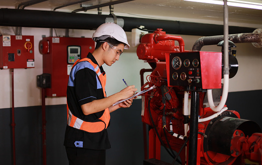 Young engineer check fire suppression system in control room of factory , daily check job of maintenance technician