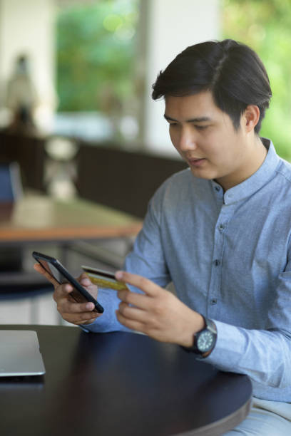 istock An asian man using his smartphone to connect with his credit card 1356285062