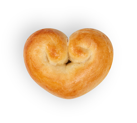 Romantic bread heart. Yeast bread bun in heart shape with egg wash. Concept for valentines day or baking with love. Traditional Swiss butter bread called Zopf or Challah. Isolated on white.