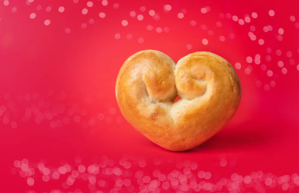 Yeast bread bun shaped like a heart. Romantic baking background. Concept for valentines day or baking with love. Traditional Swiss butter bread called Zopf or Challah.