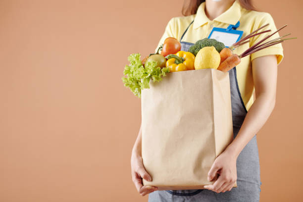 Supermarket Worker Holding Package of Groceries stock photo