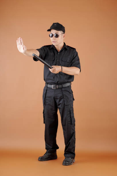 Serious confident police officer with rubber baton making stop gesture
