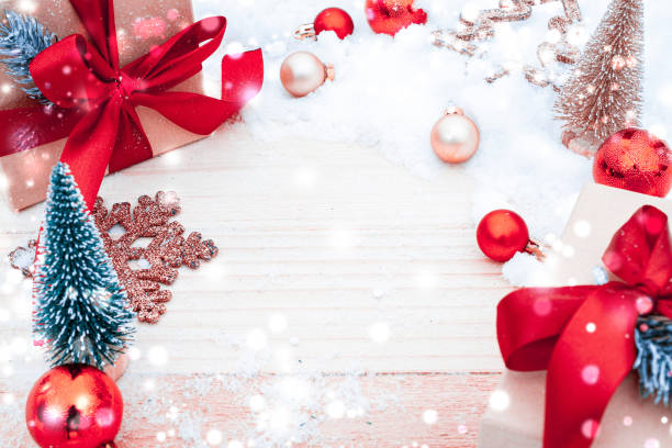 istock Xmas background table. Winter wooden decoration backdrop. Christmas board with old rustic wall, white frozen snow, golden balls and gift box. New year red bow present. 1356299863