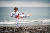 Little boy practicing karate on the beach