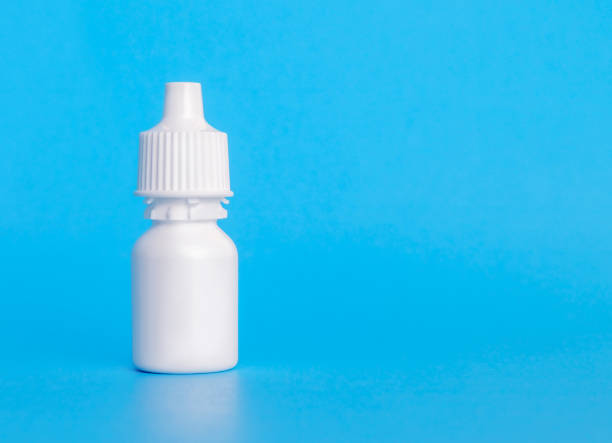 Eye drop bottle, plain, 20 ml. Single white small plastic dropper bottle. With plastic screw top. Used to dispense and store liquids. For medical treatment. Soft blue background. Copy space eyedropper stock pictures, royalty-free photos & images