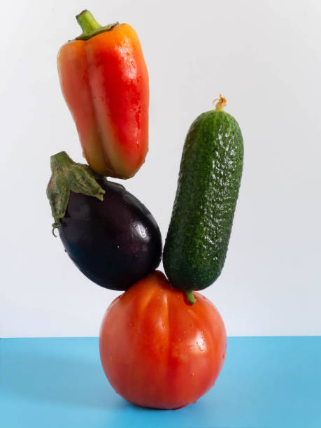 istock Fresh flying vegetables on a blue-white background. Eggplant, bell pepper, cucumber, tomato. 1356311535