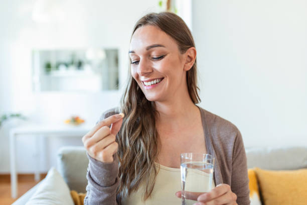 портрет счастливой женщины держит таблетку стакана воды, принимает ежедневное лекарство витамин d, добавки омега-3, кожа волос ногтей укреп� - probiotics стоковые фото и изображения