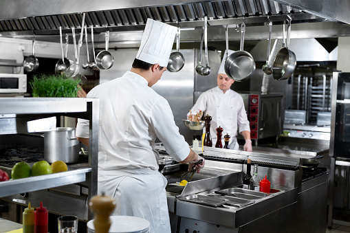 Modern kitchen. Chefs prepare dishes on the stove in the kitchen of a restaurant or hotel.