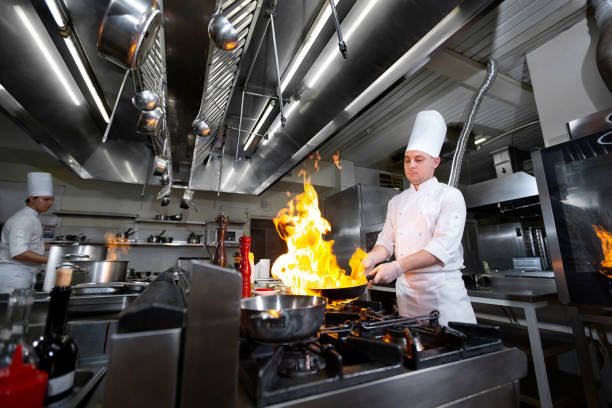 istock Chef cooking with flame in a frying pan on a kitchen stove 1356314732