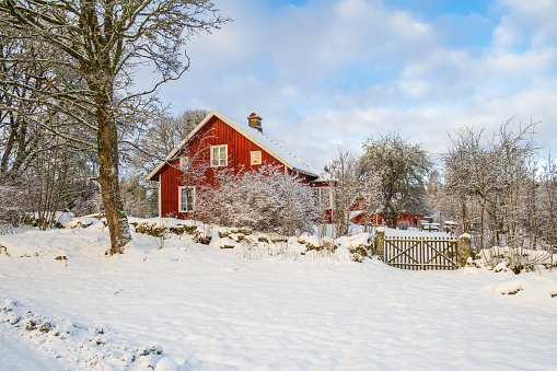 Red house with a gate in snowy winter landscape