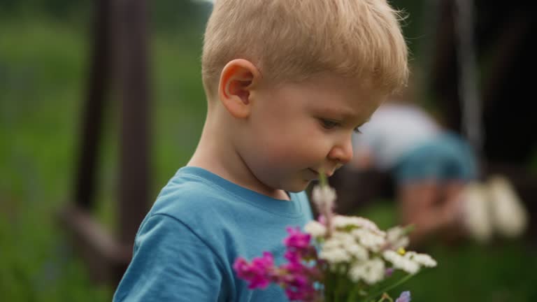 Boy with flowers breathes deeply with sister on ground