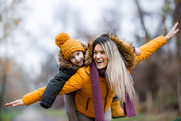 istock Cheerful single mother and her small son having fun while piggybacking in nature. 1356318593