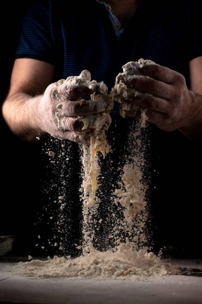 istock Male hands knead pizza dough on a dark background. 1356325287