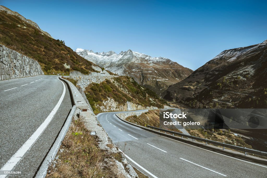 the grimsel pass road in switzerland empty winding road of grimsel pass in the swiss alps, the famous furka pass in the background Adventure Stock Photo