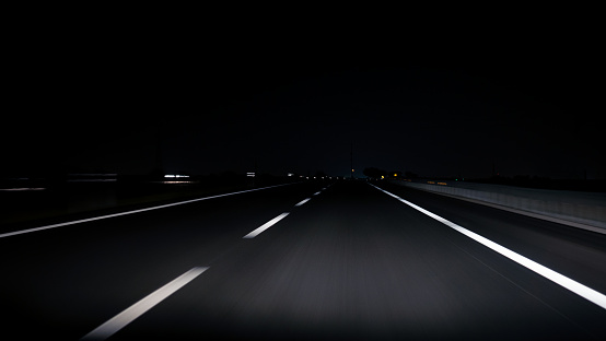 POV view of car driving on road of highway at night in Spain. Drive on an empty road in the dark evening. A car drives on a freeway. Asphalt with white line at new road.