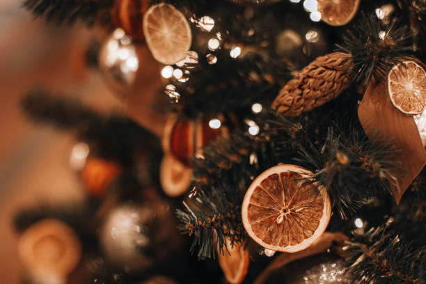 istock Creative Christmas tree decorated with dry oranges and pine cones. Magic cozy details and golden bokeh lights on background. 1356328819