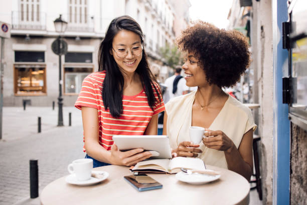 istock Two friends on vacation using tablet at the sidewalk cafe 1356329124