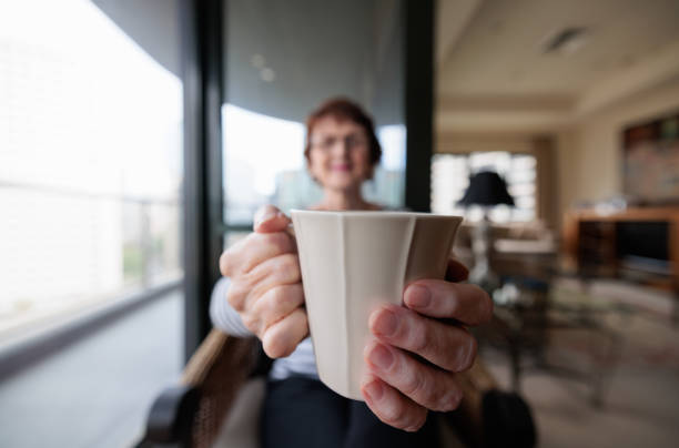 Lady's hands are holding glasses.Coffee time