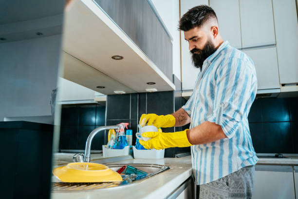 istock Young man washing dishes at home 1356333144