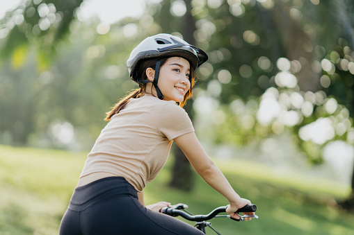 Young healthy woman exercising on bicycle in public park