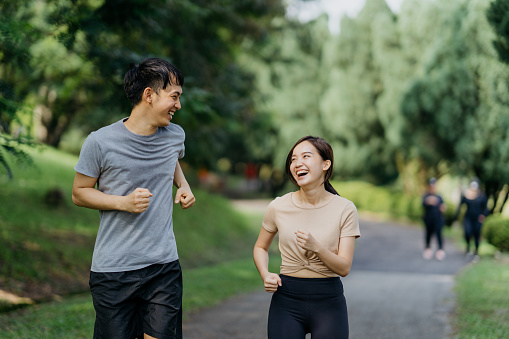 Healthy Asian couple jogging in public park