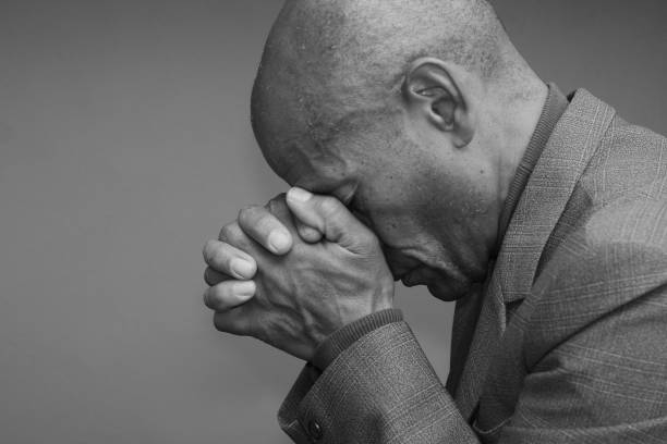 istock man praying with hands stock photo 1356334030