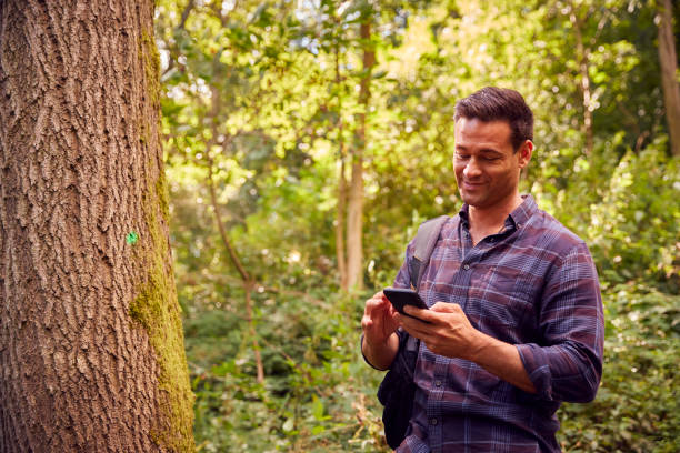 istock Man In Countryside Hiking Along Path Through Forest Using Map App On Mobile Phone To Navigate 1356334043